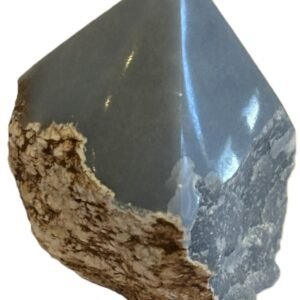 Natural rough Angelite freeform crystal with unpolished sides and a smooth polished blue point standing on a white background
